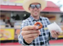  ?? LEAH HENNEL ?? Kyle Corner, Stampede manager of programmin­g entertainm­ent, gets ready to dive into a bag of mini doughnuts.