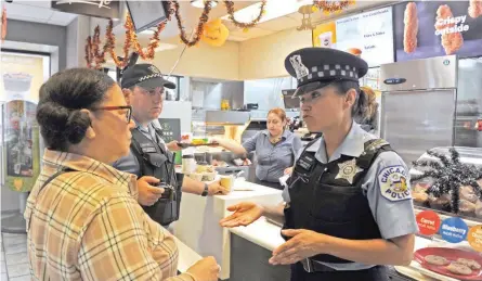  ?? — AFP ?? Chicago resident Lee Maglaya (L) meets with police officers Librada Godinez and David Hallock, at a McDonald’s restaurant during a nationwide “Coffee with a Cop” day, in Chicago, Illinois, on Thursday.