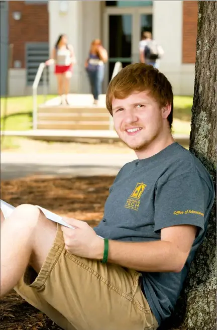  ?? NICK HILLEMANN/RIVER VALLEY & OZARK EDITION ?? Clay Wyllia of Atkins, a senior at Arkansas Tech University in Russellvil­le, sits under a tree on campus. Wyllia, who works in the Office of Admissions as a tour guide, said he was excited to hear this fall that a record enrollment of 11,000 was...