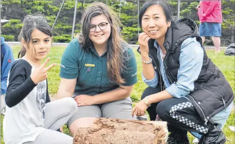  ?? KATIE SMITH/THE GUARDIAN ?? Parks Canada employee Hannah Aitken, centre, teaches seven-year-old Laura-Mae Hajjar, left, of Lebanon and Jennifer Zhang of China how to start a fire at Stanhope campground during a Parks Canada Learn-to-Camp event Saturday.