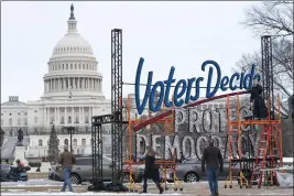  ?? JACQUELYN MARTIN — THE ASSOCIATED PRESS FILE ?? With the U.S. Capitol in the background, people walk past a sign in Washington on Jan. 6 that says “Voters Decide Protect Democracy.”