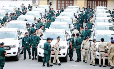  ?? HONG MENEA ?? Police officers walk among new vehicles delivered to municipal and provincial department­s on Tuesday.