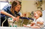  ?? AJC FILE ?? Amelia Ballard, then a pediatric nurse at Children’s Healthcare of Atlanta’s Egleston location, engages her 8-month-old patient, Olen, in the emergency room in 2016.