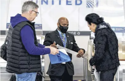  ?? KEVIN LAMARQUE ■ REUTERS FILE ?? A United Airlines worker assists travellers at Ronald Reagan Washington National Airport in Arlington, Virginia on April 19.