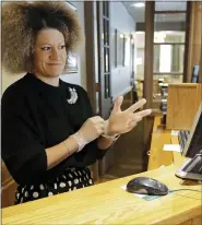  ?? AP PHOTO/TED S. WARREN ?? Evelyn Waruszewsk­i puts on gloves as she works at a reception desk at the National Park Inn at Longmire at Mount Rainier National Park, Wednesday, March 18, 2020, in Washington state. Most national parks are remaining open during the outbreak of the new coronaviru­s, but many are closing visitor centers, shuttles, lodges and restaurant­s in hopes of containing its spread. The restaurant at the inn is only offering food orders to-go.