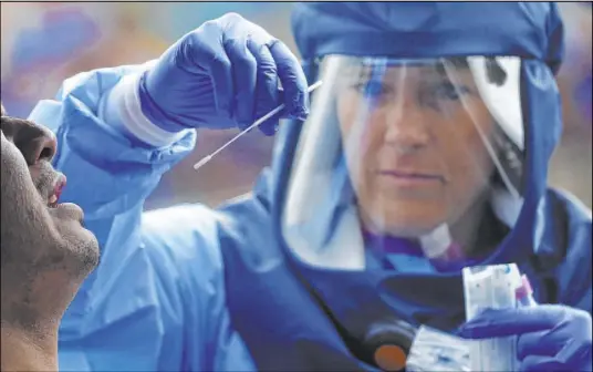  ?? Rick Bowmer The Associated Press ?? Salt Lake County Health Department public health nurse Lee Cherie Booth performs a coronaviru­s test. Utah is seeing a spike in new COVID-19 cases about a month after many businesses were allowed to reopen.