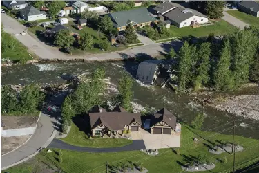  ?? AP PHOTO/DAVID GOLDMAN, FILE ?? FILE - A house sits in Rock Creek after floodwater­s washed away a road and a bridge in Red Lodge, Mont., in Red Lodge,