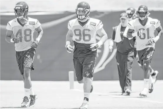  ?? Brett Coomer / Houston Chronicle ?? Practice squad players DE Dan Pettinato, center, and LB Eric Lee, right, hit the field for a rookie minicamp. Jarrell McKinney, left, is no longer on the team.