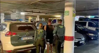  ?? ?? Dos agentes trasladan al coche de la Guardia Civil a uno de los detenidos.