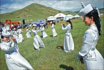  ?? PROVIDED TO CHINA DAILY ?? Performers in Mongolian costumes take pictures while awaiting delegation­s to the traditiona­l nomadic Naadam festival just outside Ulaanbaata­r, Mongolia.