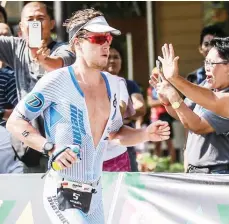  ??  ?? SINALUBONG ng mga tagahanga si Markus Rolli ng Germany sa kanyang pagtawid sa finish line at pagwagian ang Alveo Iron Man Pros Men’s Division, habang agaw-pansin ang Pinoy athete (kanan) sa elite class nitong Linggo sa Azuela Cove sa Davao City.