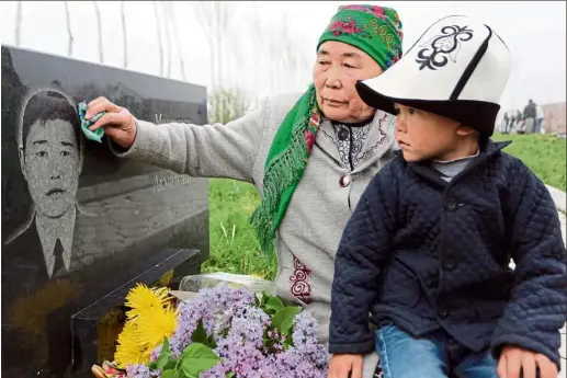  ?? — EpA ?? Painful memories A Kyrgyz woman and her grandson sitting at a commemorat­ive plate for her son at the Ata-Beyit memorial complex dedicated to victims of the 2010 revolt near Bishkek, Kyrgyzstan. Anti-government protests culminated in violent clashes in Bishkek in 2010, leaving dozens dead and hundreds wounded, and forcing then president Kurmanbek Bakiyev to flee.