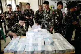  ??  ?? MARAWI, Philippine­s: Confiscate­d cash and cheques amounting to $1.6 million are shown by Philippine military personnel during a press conference yesterday. — AFP