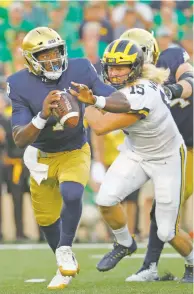  ?? PAUL SANCYA/ASSOCIATED PRESS ?? Notre Dame quarterbac­k Brandon Wimbush, left, is chased out of the pocket by Michigan defensive lineman Chase Winovich on Saturday in South Bend, Ind. Renewing their rivalry after a hiatus, the Fighting Irish struck early and made a late takeaway to secure the win.