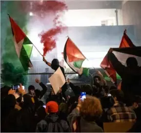  ?? PHOTOS: JOHN NGUYEN ?? Intimidati­on tactics: A mob outside Cambridge University shouts Hamas slogans and sets off flares as the Israeli ambassador tries to speak inside