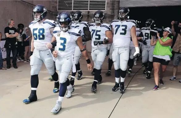  ?? MARK ZALESKI/THE ASSOCIATED PRESS ?? Seattle pivot Russell Wilson, front, and centre Justin Britt walk to the field with arms linked before the Seahawks’ game last Sunday in Nashville.