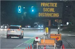  ?? JONATHAN HAYWARD THE ASSOCIATED PRESS ?? A road sign reminds drivers, cyclists and pedestrian­s alike about “social distancing,” a term that suddenly became a part of everyday speech around the world since the coronaviru­s outbreak began.