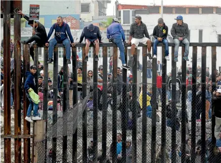  ?? AP ?? Central American migrants sit on top of the border wall on the beach during a gathering of migrants living on both sides of the border yesterday in San Diego.