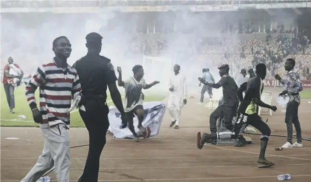  ?? ?? ↑ Police fire tear gas to deter pitch invaders at the end of the Nigeria v Ghana World Cup play-off second leg at Moshood Abiola Stadium in Abuja