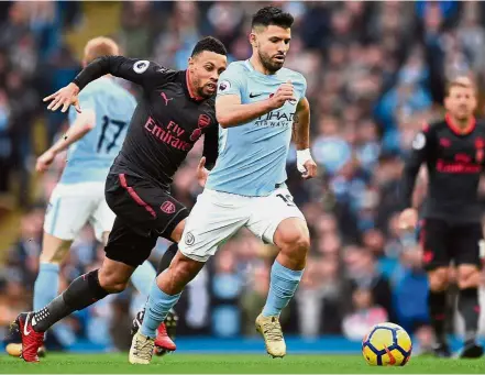  ?? — AFP ?? I’m too fast for you: Manchester City’s Sergio Aguero dribbling away from an Arsenal player during the English Premier League match at the Etihad yesterday. Manchester City won 3-1.