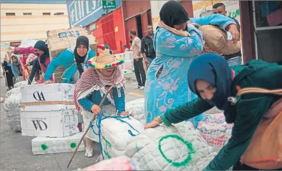  ?? JORGE GUERRERO / GETTY / ARCHIVO ?? Mulas de carga. Un grupo de mujeres prepara los fardos para cargarlos como equipaje de mano mientras los hombres miran junto al paso del Tarajal