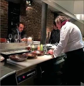  ??  ?? Dans son établissem­ent, le chef Bruno Verjus prépare ses assiettes en face de ses clients.