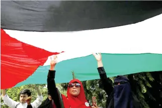  ??  ?? Indonesian­s hold a Palestinia­n flag during a rally in Jakarta. (File photo/ Reuters)