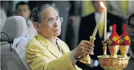  ?? Picture: REUTERS ?? MYSTIQUE OF MONARCHY: King Bhumibol lights a candle in honour of his father, Prince Mahidol Adulyadej, in 2006
