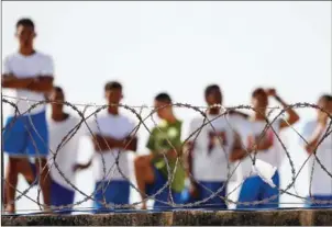  ?? ANDRESSA ANHOLETE/AFP ?? Inmates are seen behind barbed wire in the Alcacuz Penitentia­ry Center on Januray 20.