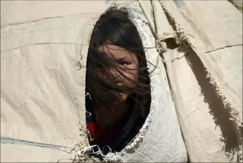 ?? Rahmat Gul/Associated Press ?? An Afghan girl, who fled her home due to fighting between the Taliban and Afghan security personnel, peers from her makeshift tent July 8 at a camp on the outskirts of Mazar-e-Sharif, northern Afghanista­n.