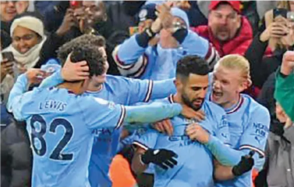  ?? ?? Riyad Mahrez is swarmed by his Manchester City teammates and cheered on by fans after his game-winning first goal on January 20, 2023.
