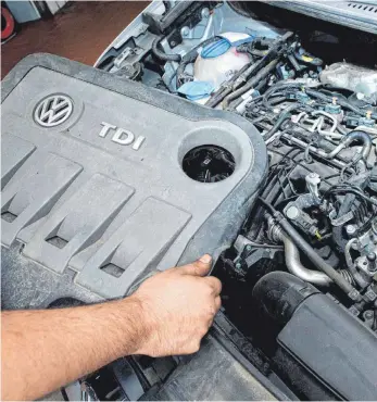  ?? FOTO: JULIAN STRATENSCH­ULTE/DPA ?? Mechaniker mit der Abdeckung des VW-Dieselbetr­ugsmotors EA189: Der Dieselskan­dal, der beim Volkswagen­konzern begann, hat das Ende der Verbrenner beschleuni­gt.