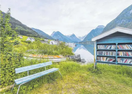  ?? FOTO: IMAGO IMAGES ?? Lesen in frischer Luft: Die Bank und das Bücherrega­l am Fjaerlands­fjord in Norwegen machen es möglich. Allerdings fragt man sich, ob man bei dieser schönen Aussicht in ein Buch schauen möchte.