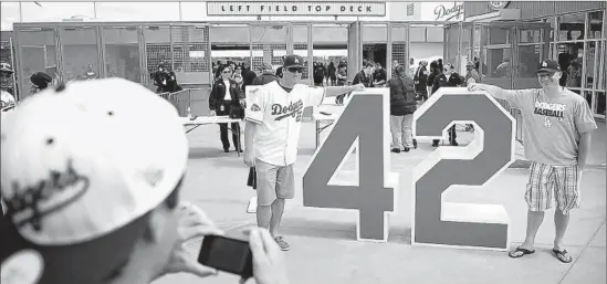  ?? Christina House For The Times ?? JACKIE ROBINSON’S retired No. 42 lures Dodgers fans Greg Webb and Greg Baker, right, for a photo op before the home team’s 4-0 victory.
