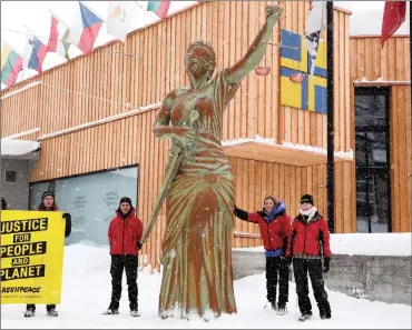  ?? PHOTO: REUTERS ?? Members of Greenpeace display a banner after they placed a statue of Justice in front of the congress centre, the venue of the upcoming World Economic Forum in the mountain resort of Davos, Switzerlan­d.