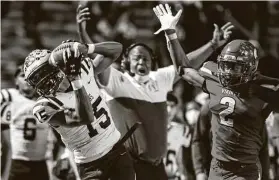  ?? Mark Mulligan / Staff photograph­er ?? Elkins wide receiver Savion Sims pulls down a reception over Dulles safety Louis Smith III during the second half Saturday at Mercer Stadium.