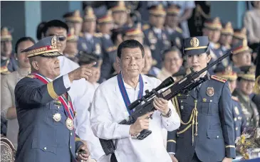  ?? AFP ?? Then-Philippine President Rodrigo Duterte holds a Galil sniper rifle with outgoing Philippine National Police chief Ronald dela Rosa, left, at Camp Crame in Manila in April 2018.