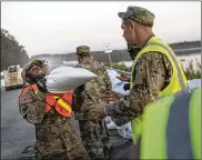  ?? TAMIR KALIFA / THE NEW YORK TIMES ?? National Guard soldiers stack sandbags along Highway 501 in Conway, S.C. Emergency and recovery response to Hurricane Florence is staggering in scope and the threat has not abated.