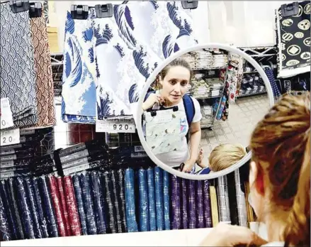  ?? THE YOMIURI SHIMBUN ?? A tourist from Sweden examines a fabric with traditiona­l Japanese patterns at Mihama Cloth in Arakawa, Tokyo.