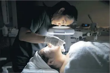  ?? Photograph­s by Allen J. Schaben Los Angeles Times ?? LIZETH ARIAS gives a facial to her sister Sarahit Morales at Advance Beauty College. The Little Saigon school was originally called Tam’s Beauty School, according to a Vietnamese naming tradition.