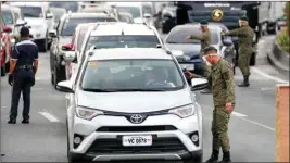  ?? PTI ?? Army troopers use a thermal scanner to check the temperatur­es of people entering the metropolis at a checkpoint on the outskirts of Quezon city, Philippine­s Sunday