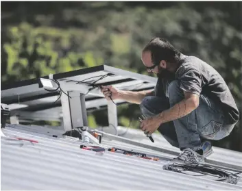  ?? AP PHOTO/DENNIS M. RIVERA PICHARDO ?? A technician installs a solar energy system at a home in 2018, in Adjuntas, Puerto Rico.