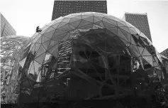  ??  ?? A worker cleans the exterior of one of three glass spheres at Amazon headquarte­rs in Seattle. — WP-Bloomberg photos