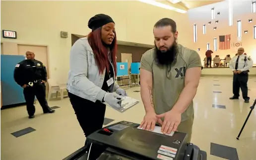  ?? AP ?? Denise Arnold, left, an early voting election official with the Chicago Board of Elections, helps Cook County jail inmate Ioan L’ela cast his ballot as he participat­es in early voting in Illinois primary in Chicago.