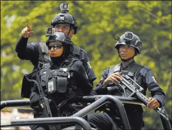  ?? Marco Ugarte The Associated Press ?? Police officers on June 21 patrol the poor neighborho­ods of Acapulco, Mexico. Heavily armed security is now common in the beach resort.