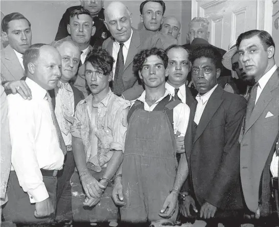  ?? CHICAGO AMERICAN PHOTOS ?? Frank Oliver, from left, in handcuffs; Fred Smith, in overalls; and David Blackstone, in dark suit, each received four life terms for the Aug. 11, 1931, murders of four teens in Michigan. The slayings became known as the Ypsilanti torch murders because the men burned the bodies to cover up their crime.