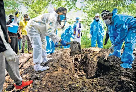  ??  ?? Volunteers dig a grave for a coronaviru­s victim during a funeral at a cemetery in Pune, India, yesterday