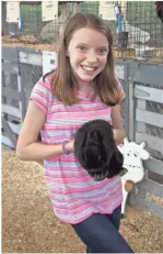  ?? / Kevin Myrick ?? Callie Ensley held up a rabbit in the livestock exhibition area run with the help of local 4-H members at the Polk County Fairground­s.