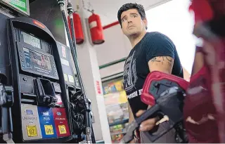  ?? JOHN MINCHILLO/ ASSOCIATED PRESS ?? Wallace Reid fuels his vehicle he drives to make a living using ride-share apps Wednesday, in the Queens borough of New York. Millions of Americans who rely on their cars for work are changing their habits, signing up for carpools or even ditching their cars for bicycles as gas prices recently hit $5 per gallon for the first time ever.