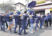  ?? Tatan Syuflana / Associated Press ?? Indonesian officers escort dozens of men arrested in Sunday’s raid on a sauna to police headquarte­rs. Similar raids have been reported around the country.
